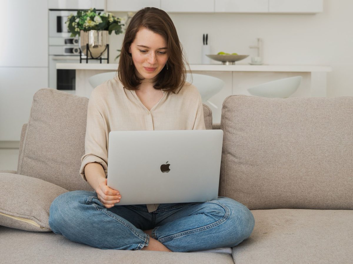 Kvinna sitter i soffan med en bärbar dator och installerar programvara hemma